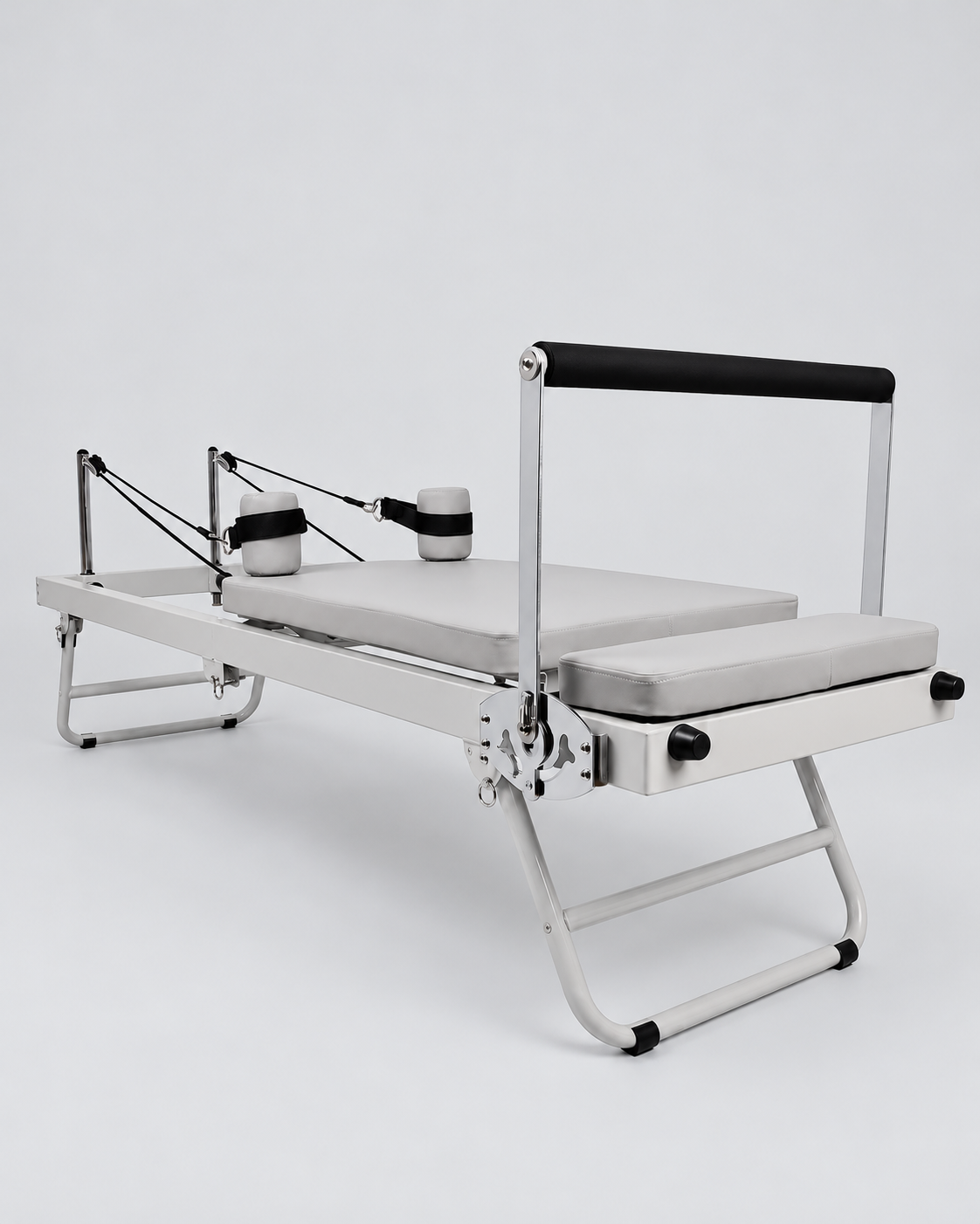 Reformer Pilates pliable compact en aluminium gris, vue d’ensemble de trois quarts.