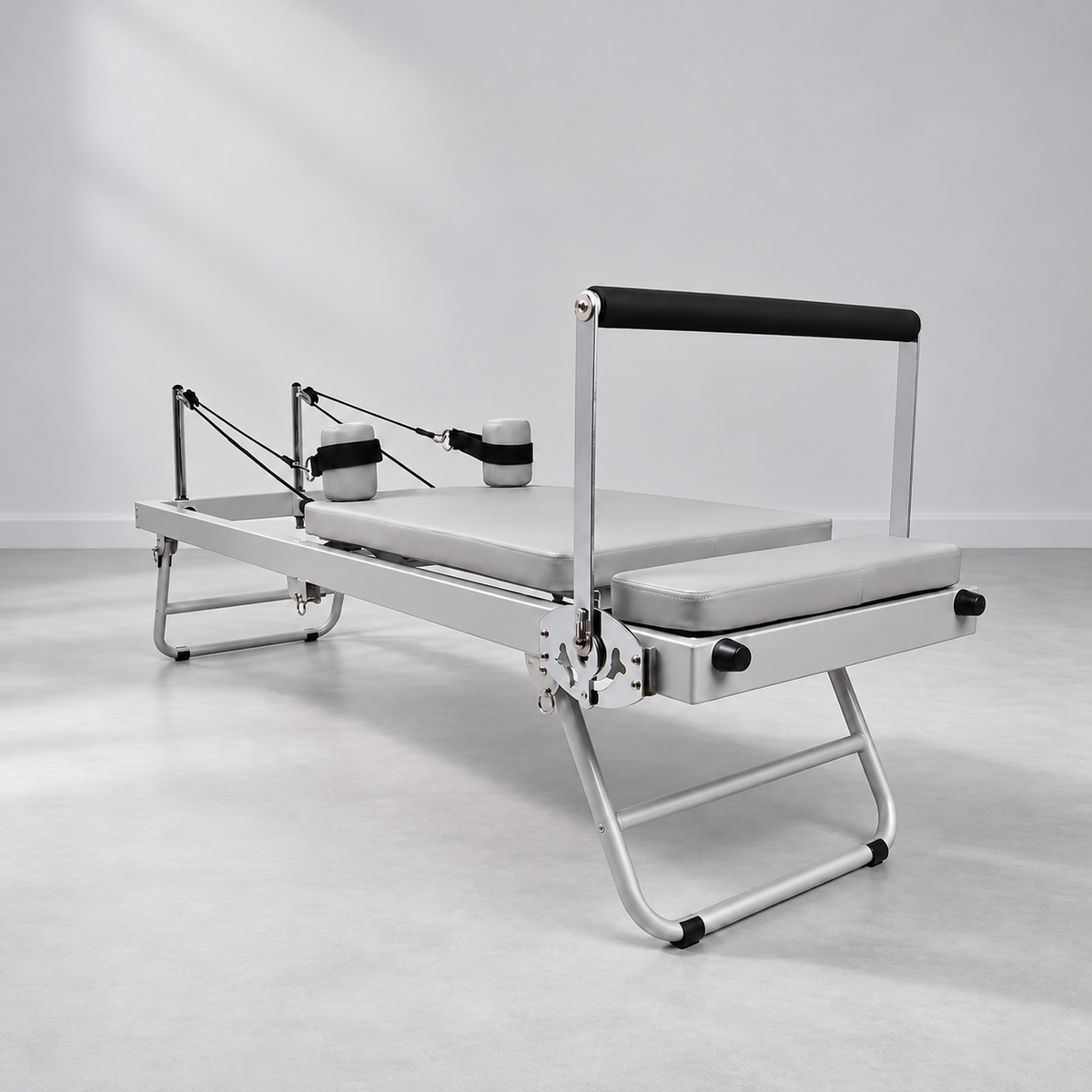 Reformer Pilates pliable compact en aluminium gris, vue d’ensemble de trois quarts.