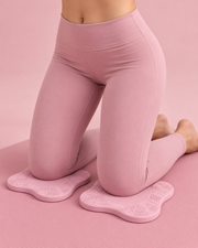 Coussinets Pilates roses placés sous les genoux