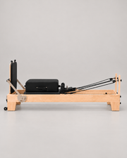 Reformer Pilates en bois fixe et sellerie noire, vue de profil