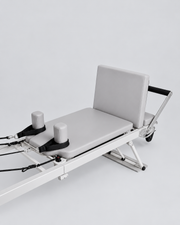 Détail du chariot gris, des appuis et de la barre de pieds du reformer en aluminium.