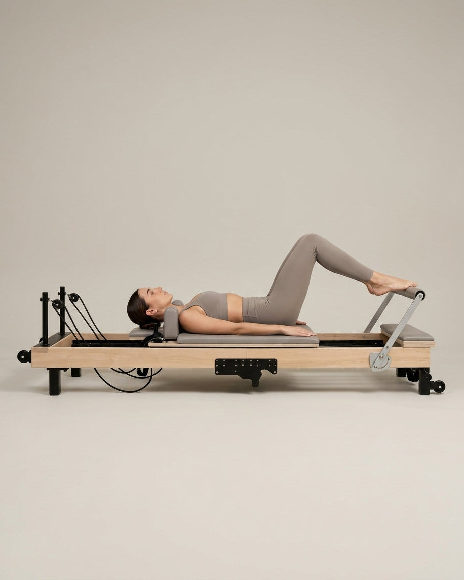 Femme faisant du footwork sur le reformer Pilates pliable Opilat coloris Galet