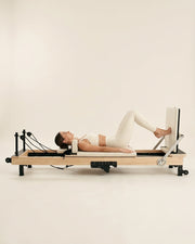Femme faisant du footwork sur le reformer Pilates pliable Opilat coloris Ivoire